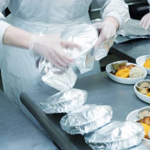 Chef is wrapping airline food in foil, professional kitchen, toned image